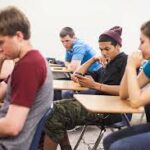 Students focusing on mobile phones in classroom