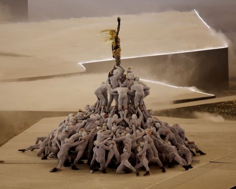 A Golden Voyager inspired by references from French history stands atop a pile of masked dancers as the last Olympic ring is raised above the stage