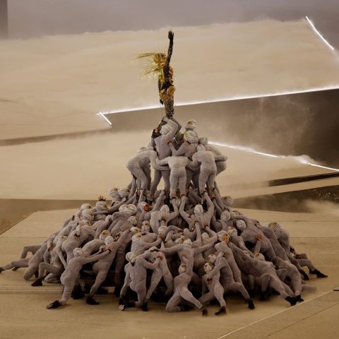 A Golden Voyager inspired by references from French history stands atop a pile of masked dancers as the last Olympic ring is raised above the stage