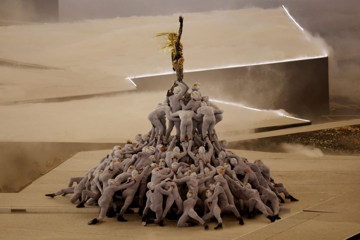 A Golden Voyager inspired by references from French history stands atop a pile of masked dancers as the last Olympic ring is raised above the stage