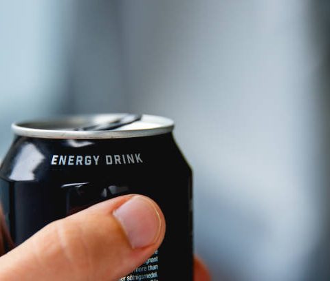 close up of a hand holding a can of energy drink